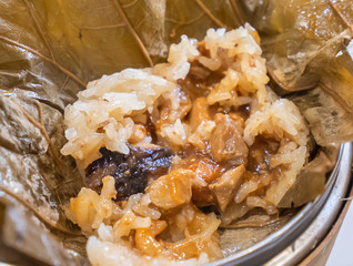 Delicious Lo Mai Gai dim sum, fresh steamed glutinous rice with chicken roll wrapped by lotus leaf in bamboo steamer in hong kong yumcha restaurant.