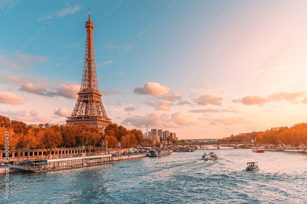 The main attraction of Paris and all of Europe is the Eiffel tower in the rays of the setting sun on the bank of Seine river with cruise tourist ships - obrazy, fototapety, plakaty 