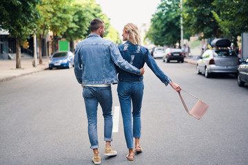 Back view of hugging couple walking away on the street