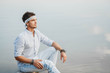 © Andriy - Man sitting on wooden bridge and looks at the water reflex of blue sky. Concept of freedom relaxation. Place for text or advertising