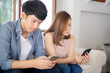 © N_studio - Young asian couple sitting on sofa with problem about relationship because addicts social network media together, asia family expression with looking phone with ignoring and indifferent.