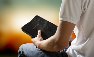 Man reading old Bible book on background