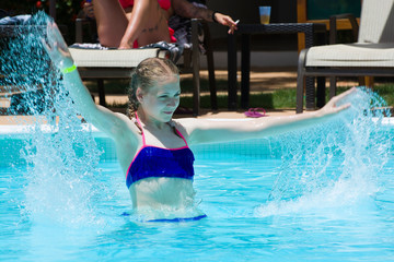 Canvas Print - Teenage girl splashing water and playing in luxury hotel swimming pool. Summer vacation concept