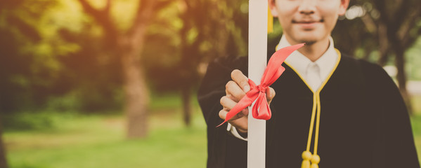 Wall Mural - Banner of happy graduate. Happy Asian man in graduation  holding diploma