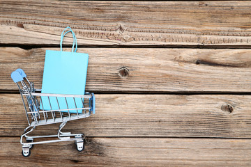 Canvas Print - Small metal cart with shopping bags on brown wooden table