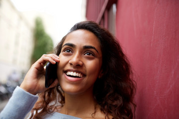 Wall Mural - smiling young Indian woman talking with cellphone outside