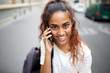 © mimagephotos - Close up beautiful young woman smiling and talking with phone on street