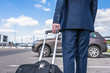 © flowertiare - Man in a blue suit with a suitcase at the airport parking on the backdrop of his car. Business trip concept
