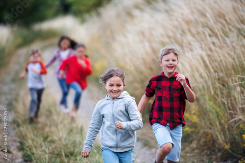Fotografía Group of school children running on field trip in nature.