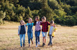 © Halfpoint - Group of school children walking on field trip in nature, arm in arm.