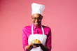 © Carlos David - Portrait of a smiling young female chef holding a plate with a freshly made croissant