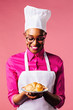 © Carlos David - Portrait of a smiling young female chef holding a plate with a freshly made croissant