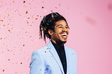 Portrait of a man with cool hair laughing, against studio background