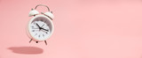 Pink Alarm clock on pastel pink background.