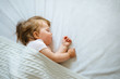 © kaloriya - Cute little baby sleeping peacefully on bed at home covered with blanket. Child daytime sleeping schedule