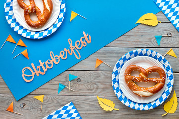 Wall Mural - Oktoberfest, pretzels on disposable plates, decorative flags and Autumn leaves