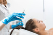 beautician holds a syringe with an rejuvenation injection on the background of the patient. A young girl is undergoing a course of spa treatments in the office of a beautician. Moisturizing, cleaning