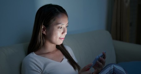 Wall Mural - Woman watch on cellphone at home in the evening