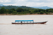 A Man Driving A Long Tail Boat On The MEKHONG River
