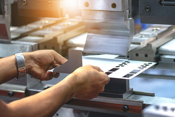 Workers bending sheet metal by CNC machines in industrial plants