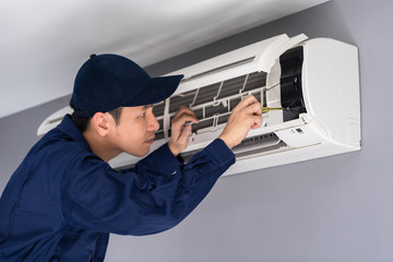 Wall Mural - Electrician with screwdriver repairing air conditioner indoors