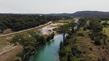 Drone Ascends Above River Bend And Then Shows Large Open Rocky Recreational Area And River Access. - Aerial Footage Of Blanco River - Wimberly, TX