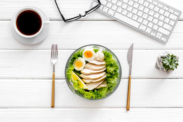 Wall Mural - Healthy dinner in bowl near keyboard and tea on white wooden background top view