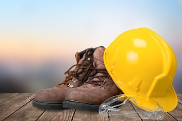 Wall Mural - Yellow working hard hat, goggles and work boots on  background