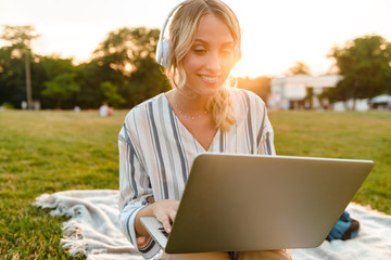 Poster - Beautiful young blonde girl relaxing on a lawn at the park