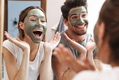 Cuadros en Lienzo Image of joyful couple standing in bathroom with face mask