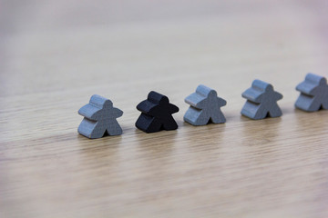 Gray gaming pieces and a black meeple, diversity concept