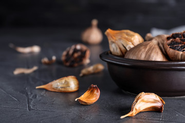 Bowl with aged black garlic on table. Space for text