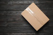 © New Africa - Closed cardboard box on black wooden background, top view. Space for text