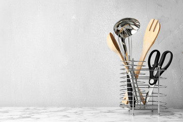 Poster - Different kitchen utensils on table against light background. Space for text