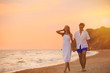 © New Africa - Young couple walking on beach at sunset