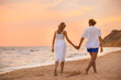© New Africa - Young couple walking on beach at sunset