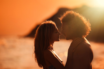 Sticker - Young woman in bikini and her boyfriend on beach at sunset. Lovely couple