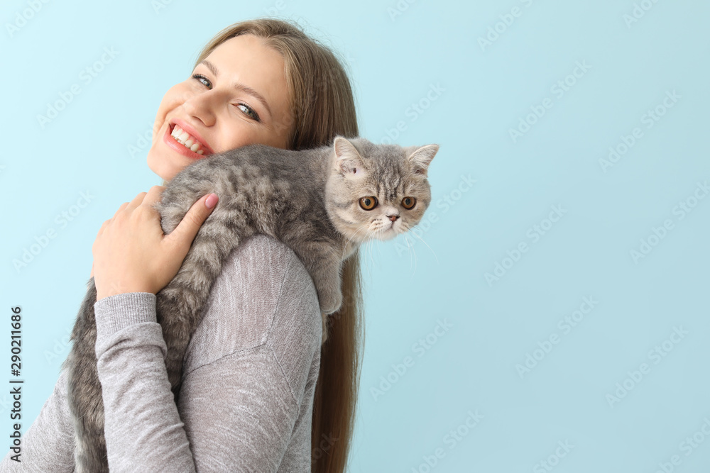 Beautiful young woman with cute cat on color background - obrazy, fototapety, plakaty 