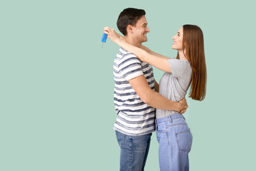 Poster - Happy couple with key from their new car on color background