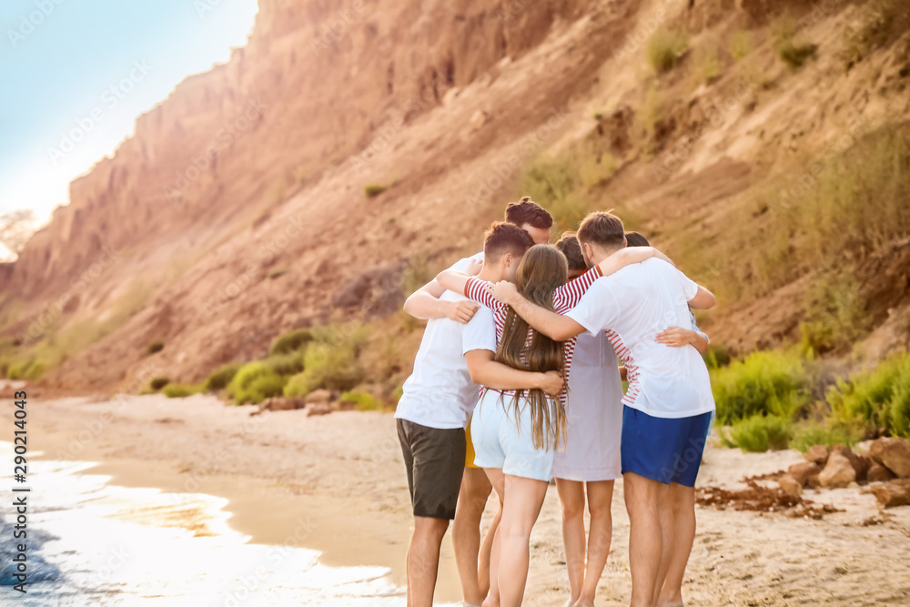 Friends hugging on sea beach at resort