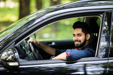 Portrait of a handsome young man driving a car on the road