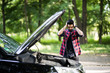© F8  \ Suport Ukraine - Closeup portrait, young indian man having trouble with his broken auto, opening hood trying to fix engine, isolated green trees outside background.