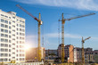 © bukhta79 - Construction site background. Hoisting cranes and new multi-storey buildings. I.ndustrial background.Building construction site work against blue sky