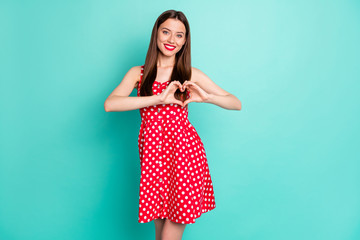 Wall Mural - Portrait of charming millennial showing her feelings care making heart with fingers wearing polka dot skirt dress isolated over teal turquoise background