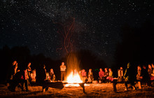 Beautiful Scenery Of Night Vision. Bonfire Around People. Basking By The Fire At Night. The Concept Of Outdoor Activities.