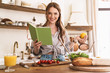 © Drobot Dean - Woman indoors at the kitchen cooking holding notebook and lemon.