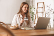 © Drobot Dean - Woman sit indoors in office using laptop computer holding credit card.