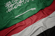 waving colorful flag of yemen and national flag of saudi arabia.