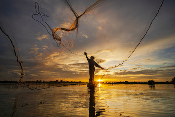 Wall Mural - Silhouette of Fisherman on fishing boat with net on the lake at sunset, Thailand