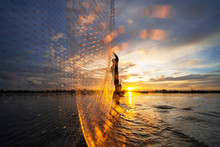 Silhouette Of Fisherman On Fishing Boat With Net On The Lake At Sunset, Thailand